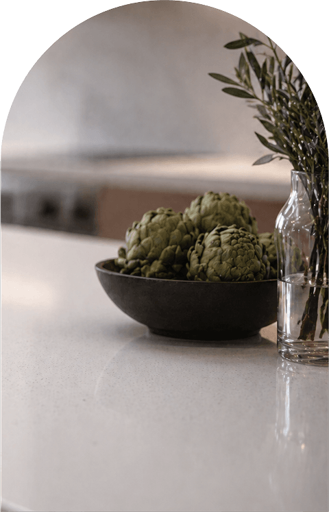 A bowl of fresh artichokes sits on a kitchen countertop, showcasing their green, spiky leaves and unique shape.